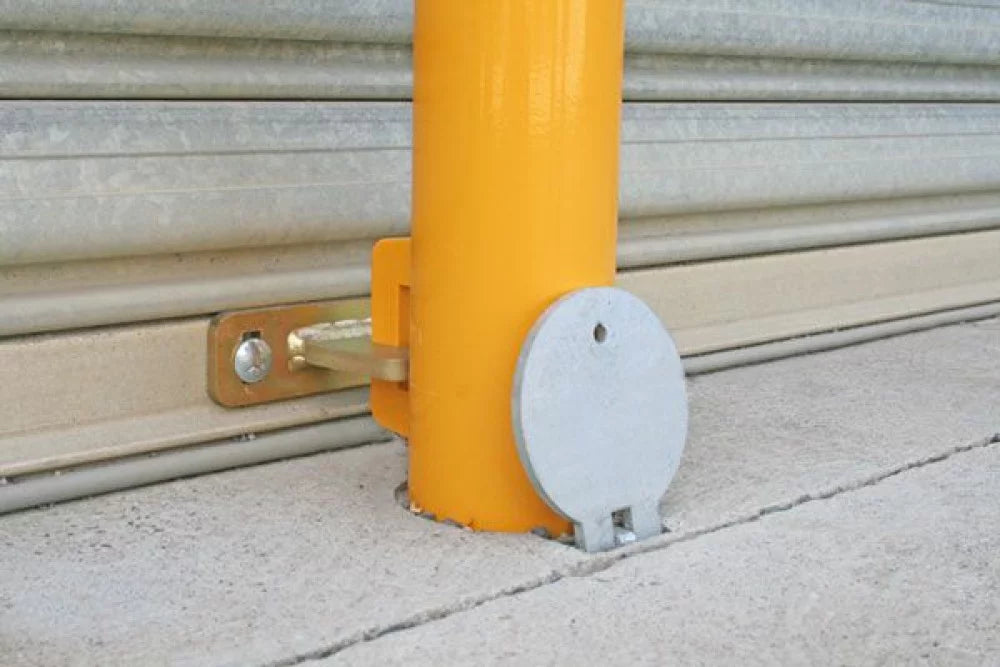 Yellow bollard with a metallic cover on a concrete surface