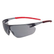 A pair of protective eyewear with a wraparound design, featuring gray smoke lenses and a black frame with red accents on the temples.