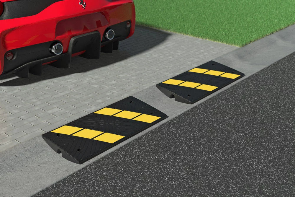 Two speed bumps with yellow stripes on a road next to a red car.