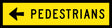 A sign with a yellow background and black text and arrow indicating the direction of pedestrian traffic.