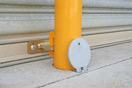 Yellow bollard with a metallic cover on a concrete surface